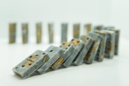 A line of dominoes arranged in a cascading pattern, some decorated with gold and gray accents.